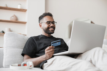 Young man using laptop computer with credit card at home. Businessman or entrepreneur working from...