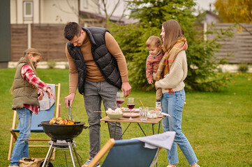 Family man cooking food for his wife and kids outdoors
