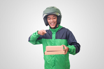 Portrait of Asian online courier driver wearing green jacket and helmet delivering package and box and pointing with finger. Isolated image on white background