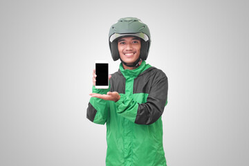 Portrait of Asian online taxi driver wearing green jacket and helmet showing and presenting blank screen mobile phone. Advertising concept. Isolated image on white background