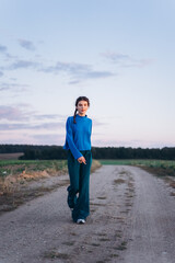 Close up portrait of young brunette girl with pigtails in blue sweater outdoors in park