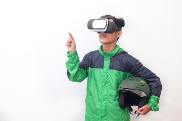 Portrait of Asian online taxi driver wearing green jacket and holding a helmet while using virtual reality or VR and pointing. Isolated image on white background