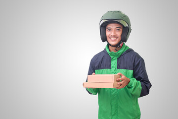 Portrait of Asian online courier driver wearing green jacket and helmet delivering package and box for customer. Isolated image on white background