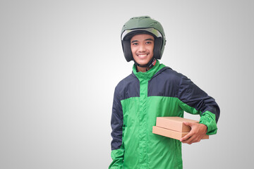 Portrait of Asian online courier driver wearing green jacket and helmet delivering package and box for customer. Isolated image on white background