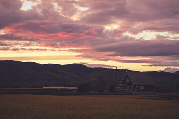 北海道の田舎の夕方の風景（山、家、空、木、畑）