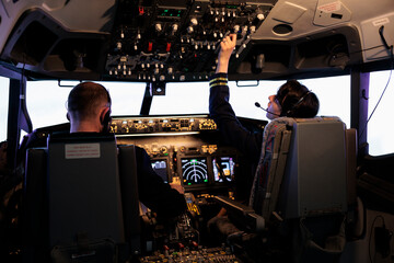 Aircrew members flying airplane with dashboard command, using control panel and navigation...