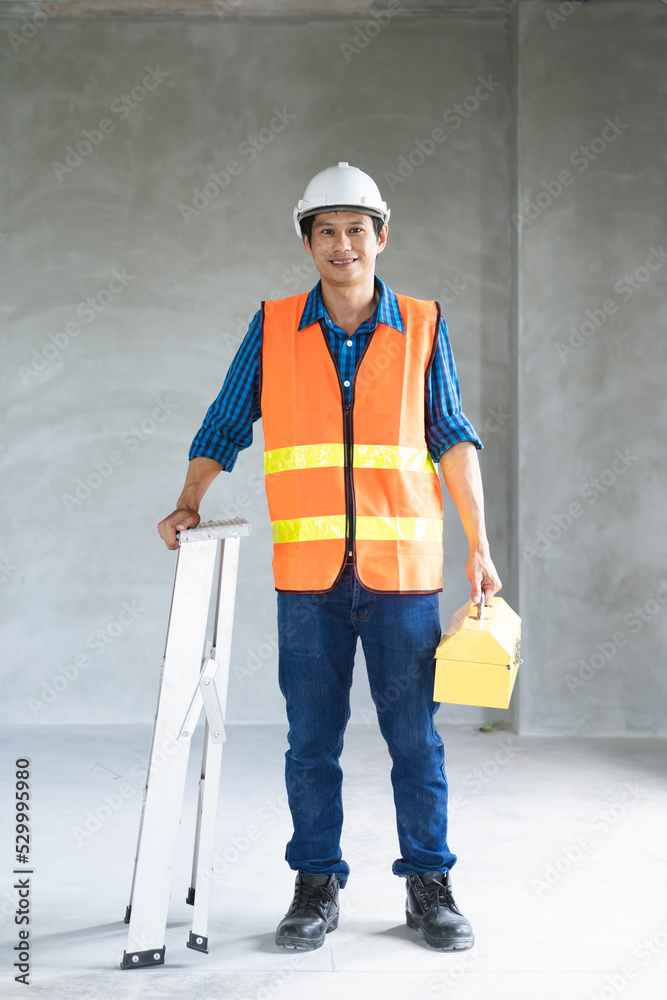 Wall mural asian professional handyman smiling and carry tools