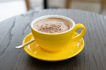 hot chocolate in yellow mug on the wooden table.