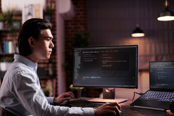 Freelancer engineer coding firewall program on monitor and laptop, using encryption server to script security network with binary code. Developing app on data text interface, it programming.