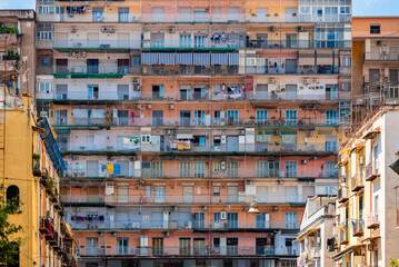 Colorful facade of a big block of flats in the old town “Centro storico“ of italian metropole Naples. Rows of balconys in over 10 floors high building near central station. Rotten old tenement house.