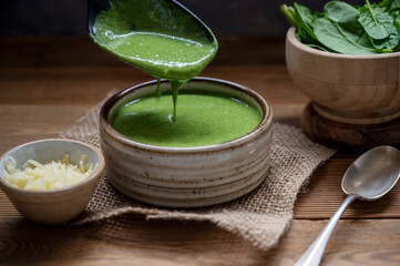 Pouring green creamy spinach soup rustic, lifestyle food, delicious vegan food.