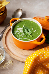 Green creamy soup. Spinach soup in orange bowl. Lifestyle food photo scene, Delicious vegan food.