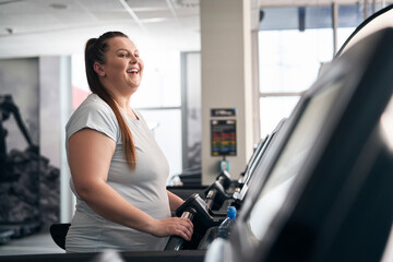 Plus size caucasian woman running on treadmill at gym