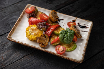 appetizing grilled vegetables on plates on a dark wooden table

