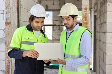 Two technician civil engineer or specialist inspector discussing, brainstorm and planing work with laptop, blueprint and walkie talkie radio together at Industrial building site. Construction concept