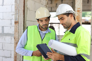 Two technician civil engineer or specialist inspector discussing, brainstorm and planing work with laptop, blueprint and walkie talkie radio together at Industrial building site. Construction concept