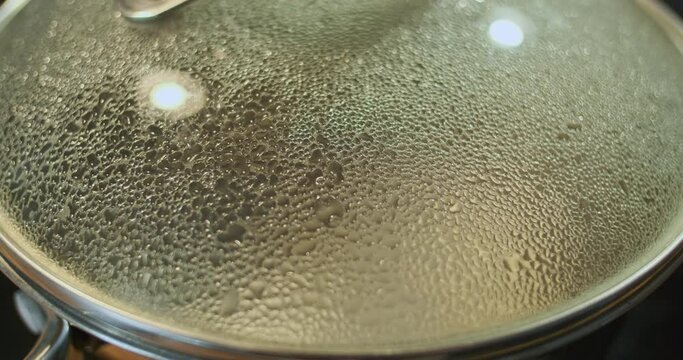 Droplets of water under the lid of the pot. Boiling water, evaporation. Close-up, the process of boiling water, the formation of hot condensate.