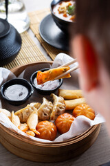 woman is eating prawns in batter in a bamboo basket.
Traditional Japanese food eaten in a restaurant.