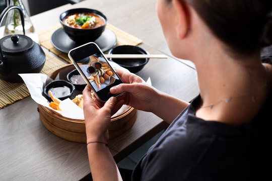 FoodPorn. A woman is taking a picture of a dish with a mobile phone
