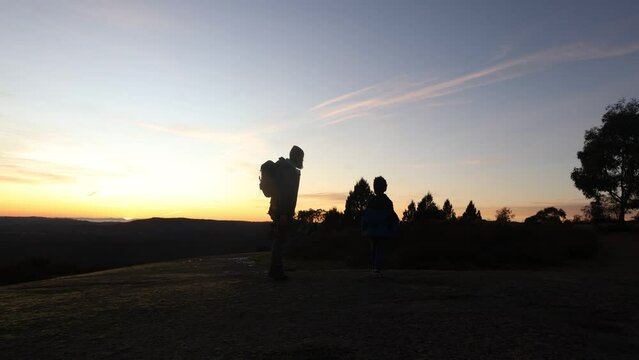 The shadows of a father and his son walking ontop of a large granite mountain in the early morning sunrise in country Australia.
