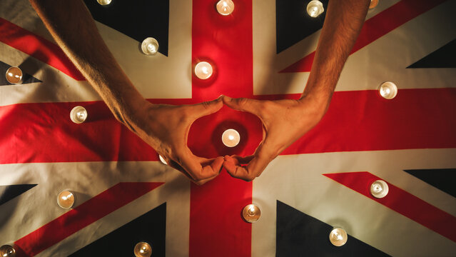Mourning candles on the flag of England with heart-shaped hand