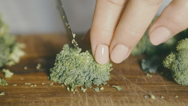 Cutting a broccoli in slow motion: you can see a wooden axe and other pieces of broccoli in the background