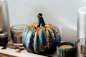 Close up Autumn, fall cozy composition. Gray pumpkin with sequins and burning candles on the wooden...