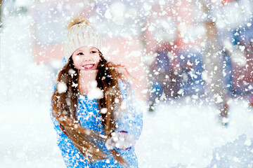 A smiling long-haired little girl is outdoors in winter.