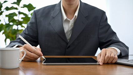 Professional Asian male boss or executive manager working at his office desk, using tablet