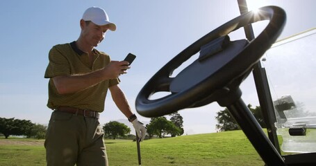 Caucasian male golfer using his smartphone on a golf course - Powered by Adobe