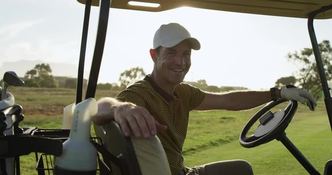 Caucasian male golfers into a golf buggy 