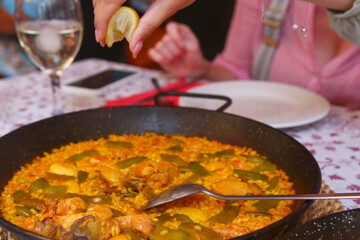 spanish paella close up photo in frying pan with shrimps, peas and lemon slice