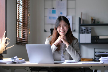 business Asian woman working online at home office and looking at the camera.