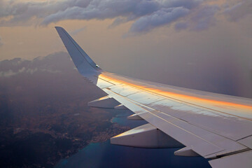 Fototapeta premium sunset seen from aircraft with reflection of sun in wing