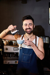 Smiling dark-hair handsome barista with beard make a coffee 