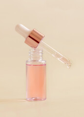 Opened Bottle with falling serum drop on light beige close up. Skincare beauty product