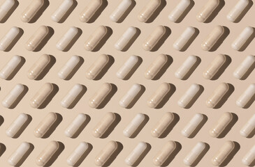 Creative pattern with capsules on light beige top view, hard shadows. Taking supplements