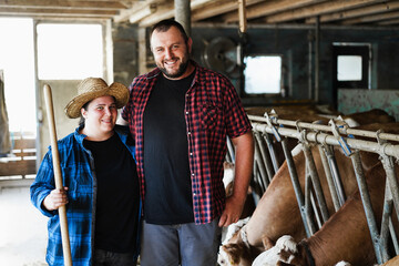 Young curvy farmers working inside cowshed - Focus on man face