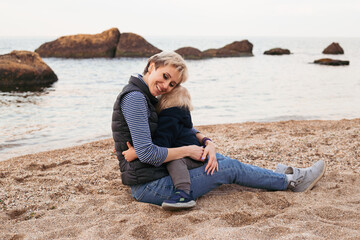 Mother and son sitting on the beach playing in autumn time
