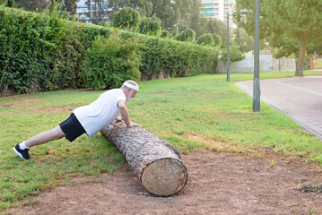 mature man practicing doing dips exercise for triceps and biceps muscle in the park. Side view shot...