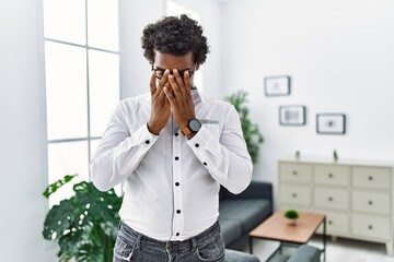 African psychologist man at consultation office with sad expression covering face with hands while crying. depression concept.