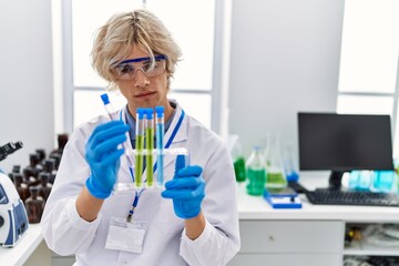 Young blond man scientist holding test tubes at laboratory