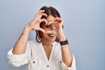 Young caucasian woman wearing casual white shirt over isolated background doing heart shape with hand and fingers smiling looking through sign