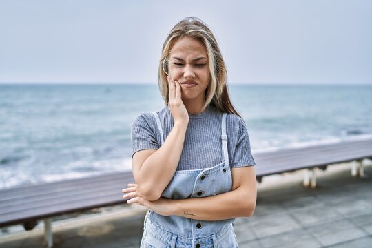 Young caucasian woman outdoors touching mouth with hand with painful expression because of toothache or dental illness on teeth. dentist