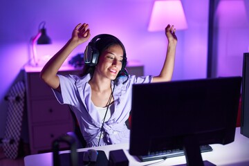 Young beautiful hispanic woman streamer listening to music dancing at gaming room © Krakenimages.com