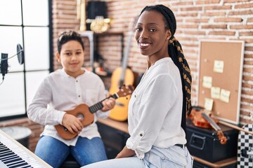 African american mother and son student learning play ukelele at music studio