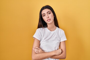 Obraz premium Young beautiful woman standing over yellow background looking sleepy and tired, exhausted for fatigue and hangover, lazy eyes in the morning.