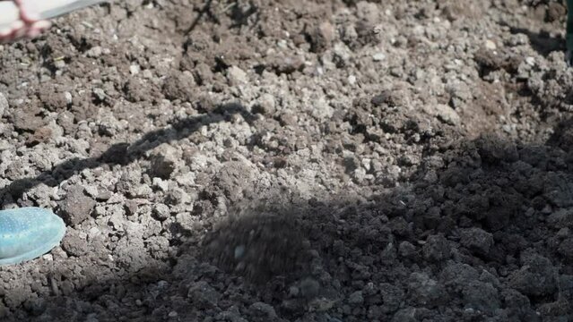Farmer digging small holes with hoe by slow motion close up shot.