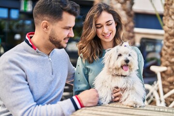 Man and woman holding dog hugging each other at coffee shop terrace