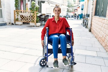 Obraz premium Young woman smiling confident sitting on wheelchair at street